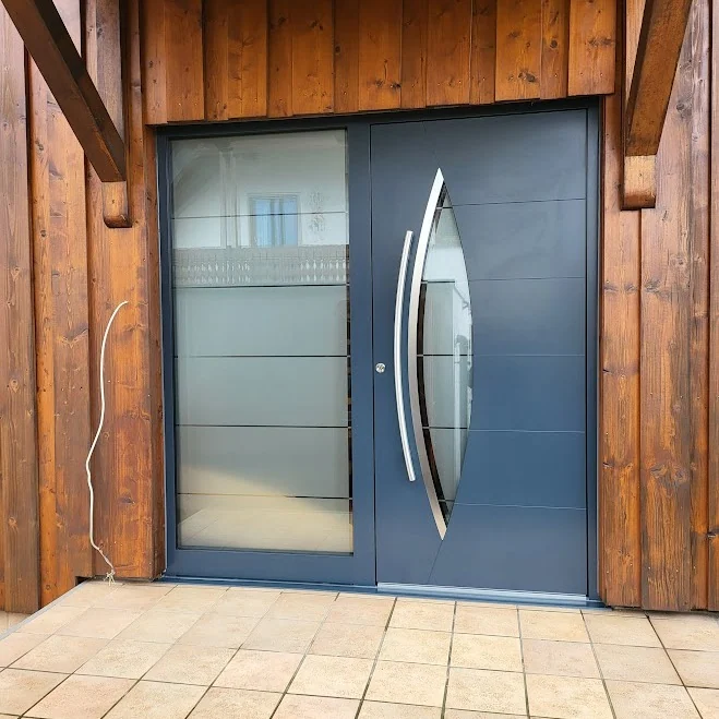 Aluminium-Haustür in RAL 7016 Anthrazitgrau mit augenförmigem Glasausschnitt und geschwungenen Edelstahl-Applikationen
