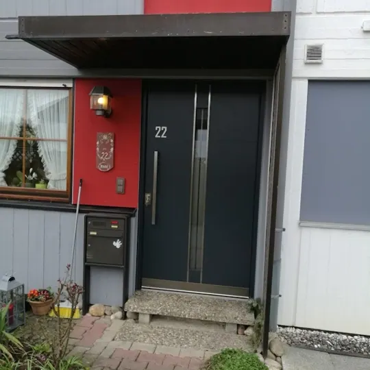 Anthrazitfarbene Inotherm Haustür vor roter Fassadenfläche