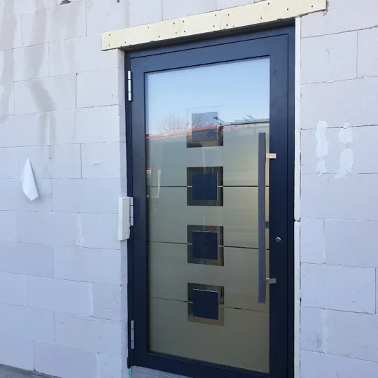 Graue Haustür mit quadratischen Glasfeldern im Rohbau