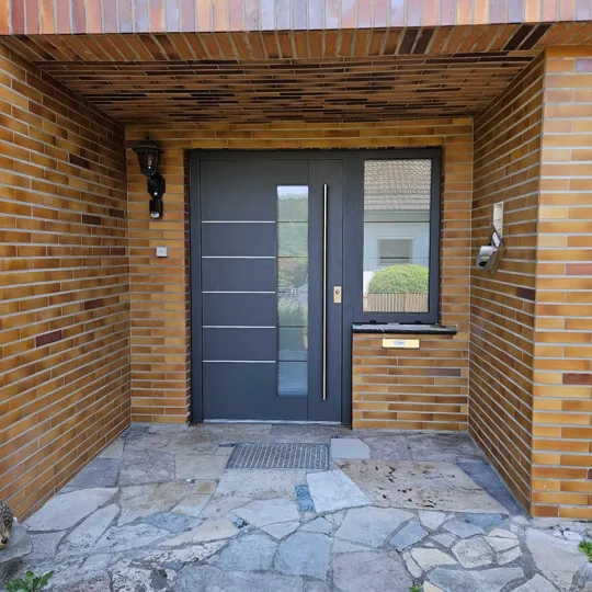 Inotherm Aluminium-Haustür in RAL 7016 Anthrazitgrau mit elegantem Glasstreifen und horizontalen Edelstahl-Applikationen