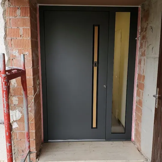 Inotherm Haustür in RAL 7021 Schwarzgrau mit schmalem vertikalen Glasausschnitt und warmem Holzdekor-Einsatz