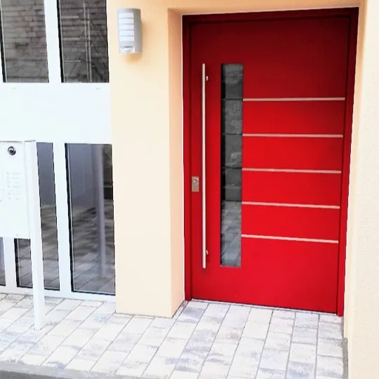 Rote Haustür mit schmalem Glasfeld und Edelstahl-Akzenten