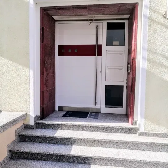 Weiße Haustür mit rotem Designakzent und integriertem Briefkasten