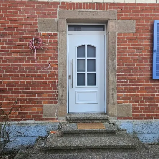 Weiße Landhaus-Haustür im Klinker-Altbau mit Sandsteingewände