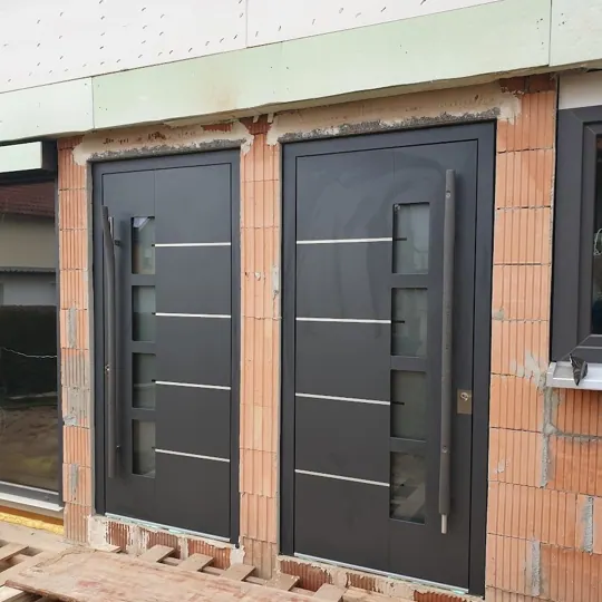 Zwei dunkle Haustüren mit Querlinien im Rohbau